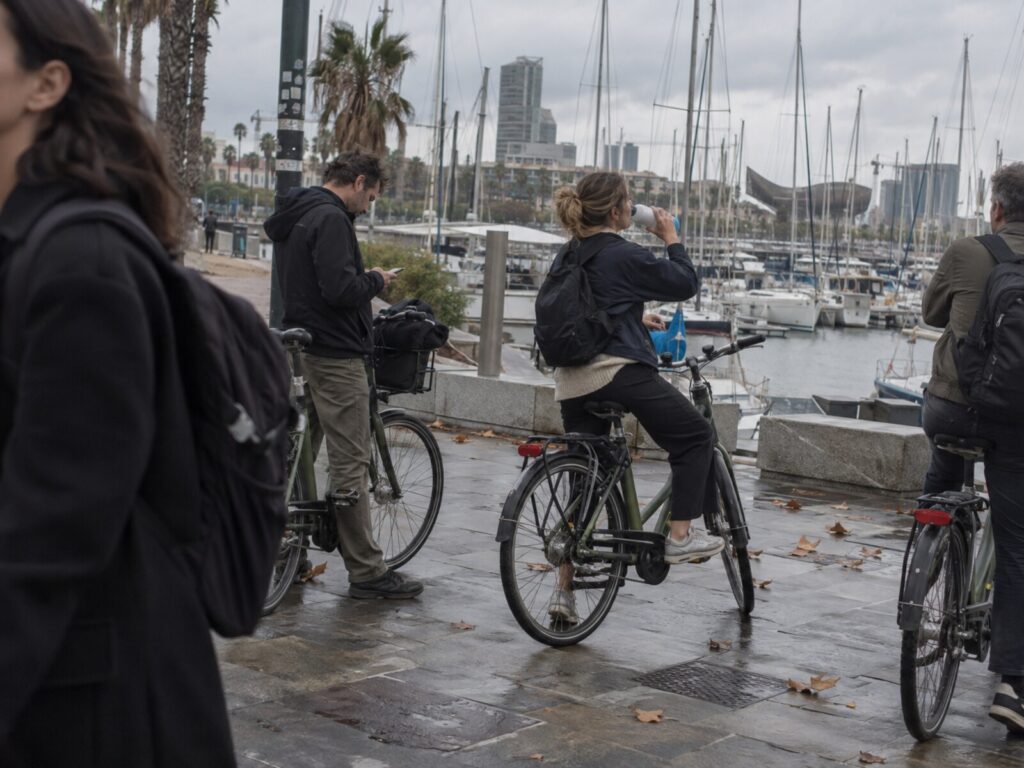 Cyclists stopping by the marina, one photographing the moored sailing boats