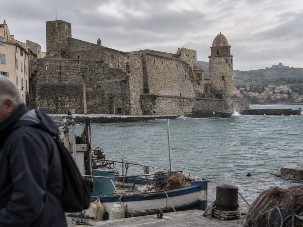 The seafront castle and bell tower above the harbour, a fishing boat moored in front