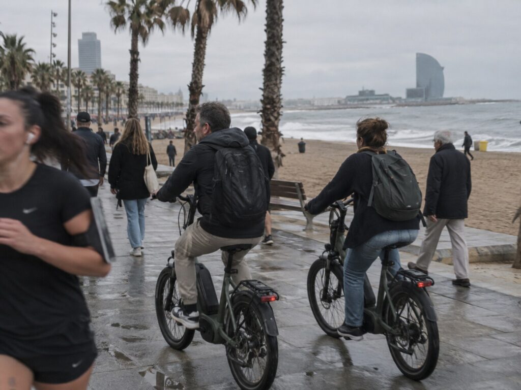 Riding electric bikes along the seafront promenade, the beach on one side