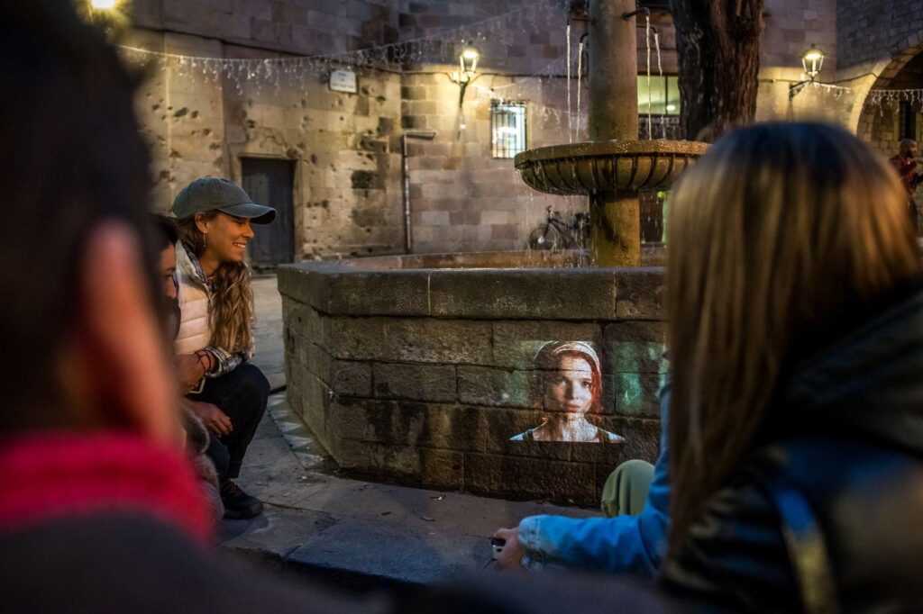 Grupo viendo una escena proyectada sobre una fuente del Gòtic de noche